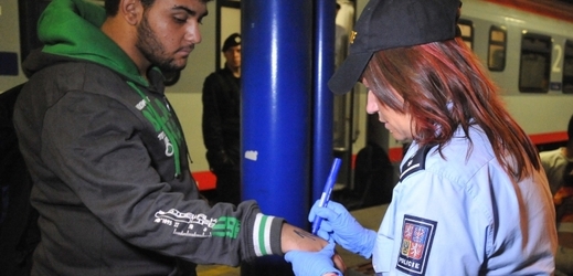 Policistka označuje na nádraží v Břeclavi jednoho z migrantů.