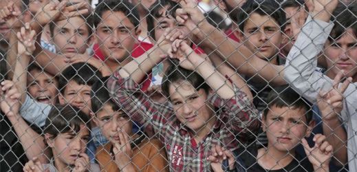 Migranti stojící za plotem v uprchlickém táboře Nizip v jihovýchodním Turecku.
