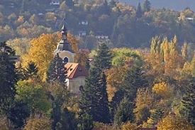 Řevnický kostel uprostřed stromy zakrytého města.