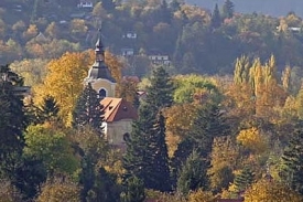Řevnick&yacute; kostel uprostřed stromy zakryt&eacute;ho města.