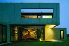 INTIMITA ZA SKLEM. Prosklené přízemí domu je otevřeno do krajiny, v patře chrání soukromí obyvatel betonová hradba.