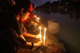 Chlapec zapaluju svíčku za oběti masakru na Filipínách.