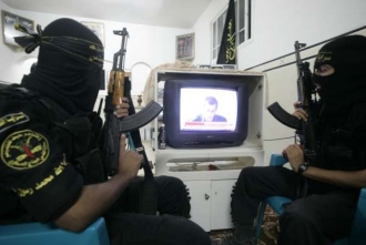 Bojovníci Hamasu se dívají na záběry Šalita v televizi.