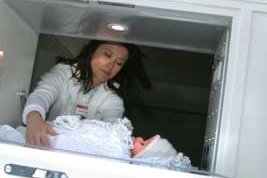Sestra vyjímá dítě z babyboxu (iustrační snímek).