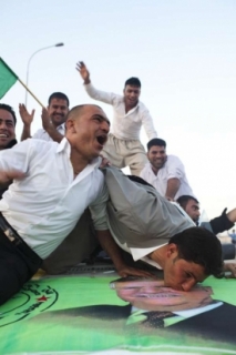 Nadšení Kurdové. Jeden líbá obrázek jejich předáka Tallabáního.