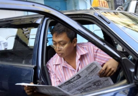 Taxikář v Rangúnu čte o novém volebním zákonu.