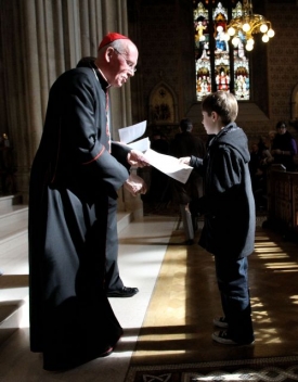 Kardinál ukazuje pastorační list mladému věřícímu.