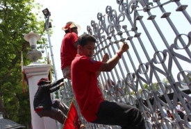 Demonstranti přelézají plot kolem areálu parlamentu.