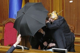 Stráž se snaží deštníkem ochránit předsedu parlamentu před vajíčky.