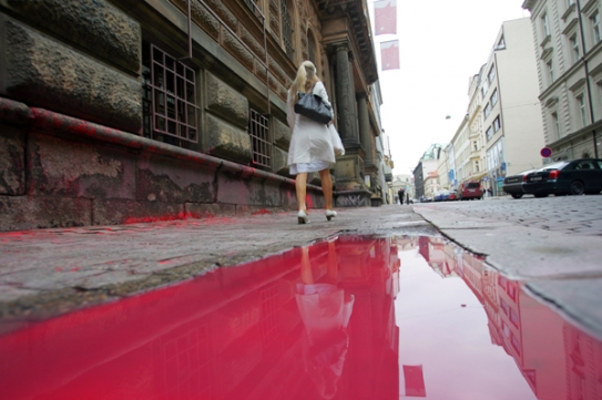 Červená barva stékající po ulici má symbolizovat krev obětí komunismu.