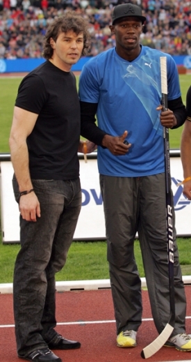 Jaromír Jágr předává Usainu Boltovi svoji hokejku.