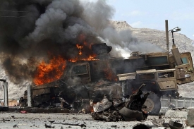Hořící obrněné vozidlo (MRAP) po útoku sebevraha na vojenskou kolonu.
