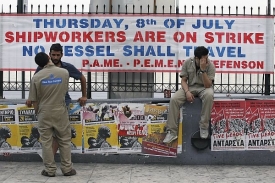 Stávkující dělníci sedí u plakátu oznamujícího, že nevyjede žádná loď.