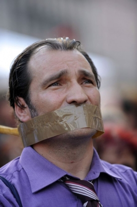 Roubík do úst novinářů chce podle demonstrantů vložit italský premiér.