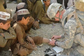 Americký voják ošetřuje afghánské chlapce.