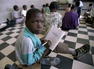 Základní škola v Mosambiku. Děti sedí na zemi.