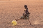 Dívka sune nohama barel s vodou, tkerý naplnila na okraji vesnice.