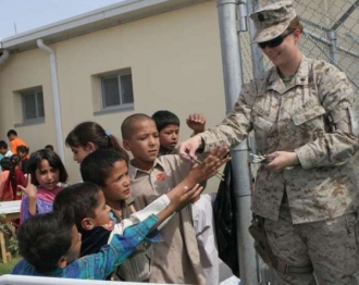 Příslušnice armády USA rozdává afghánským dětem školní potřeby.