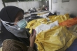 Žena s maskou poblíž těl obětí erupce sopky v nemocnici v Yogyakartě.