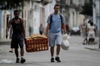 Dva muži nesou bednu s chleby v Havaně.