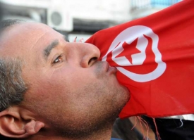 Demonstrant líbá na ulici tuniskou vlajku.