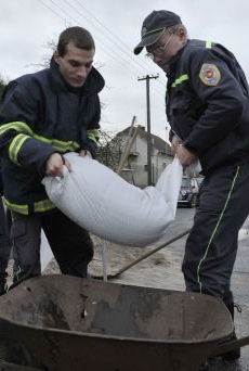 Plzeňští hasiči nosí k vodě pytle s pískem.