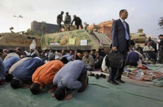 Demonstranti se modlí před obrněným vozem na Tahríru.