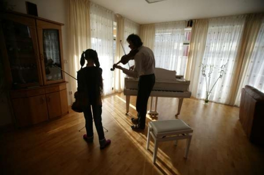 Dívka se učí na housle. Ruská rodina Žukovových v Praze.