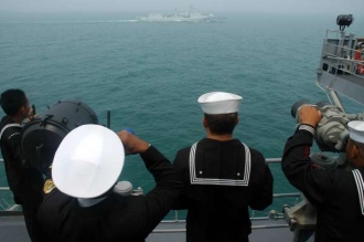 Námořníci na čínské raketové lodi Šen-zen sledují vojenské plavidlo USA. 