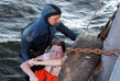 Potápěč vytahuje z vody jednu z pasažérek, která měla štěstí a tragédii přežila (Foto: Profimedia).