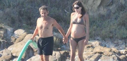 Těhotná Carla Bruniová s manželem na pláži.