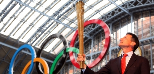 Předseda organizačního výboru Sebastian Coe pózuje s pochodní před olympijskými kruhy.