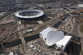 Stadiony už jsou téměř hotové, v popředí plavecký areál, v pozadí olympijský stadion. 
