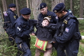Policisté odvádějí jednu z aktivistek z lokality, kde začali dřevorubci těžit.