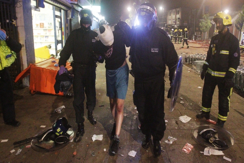 Policisté odvádějí jednoho z výtržníků (Foto: ČTK/AP).