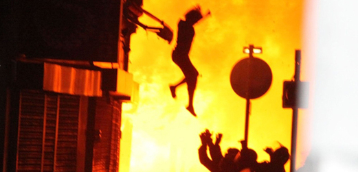 Žena skáče z okna vstříc nataženým rukám hasičů.