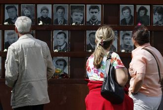 Návštěvníci památníku zdi v Bernauer Strasse se dívají na snímky zabitých.