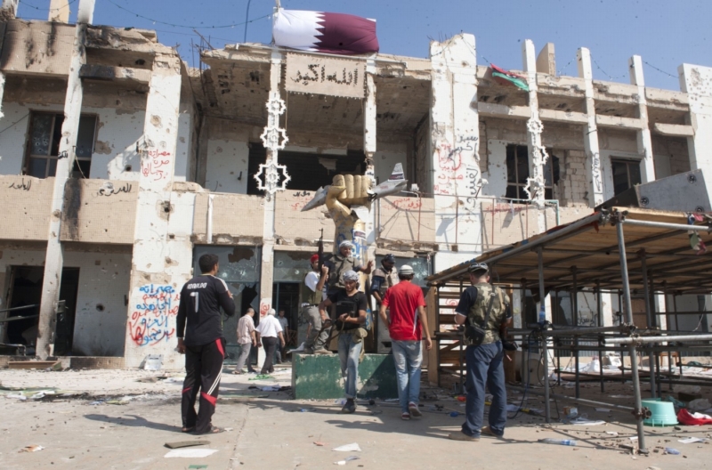 Povstalci před dobytým Kaddáfího sídlem v Tripolisu. Ze snímku je patrné, že budova byla ostřelována a bombardována NATO.