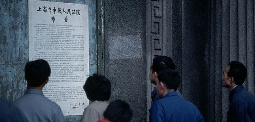 Číňané stojící před vládním seznamem informujícím o trestech smrti.