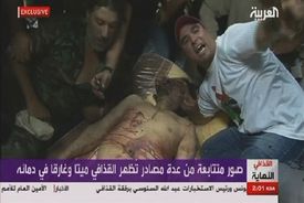 Hanobení mrtvoly. Libyjci se fotografují s mrtvým Kaddáfím.
