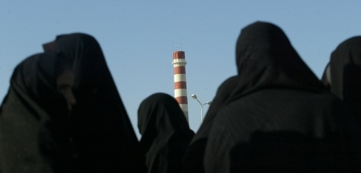 V popředí zahalené Íránky, v povzdálí komín jaderného střediska.