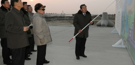 Kim Čong-il koukající na obří tabuli.