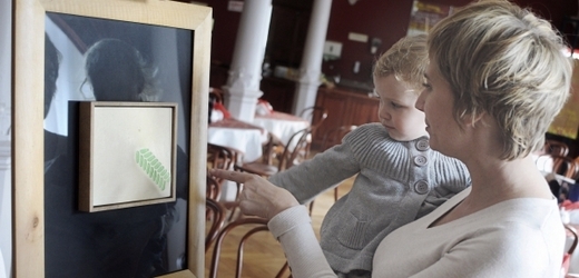Matka s dítětem si prohlížejí obraz čackého studenta umění Andrzeje Sobiepana.