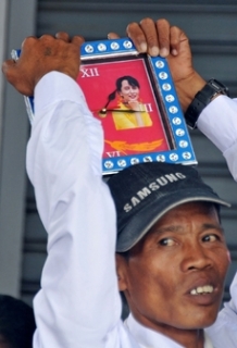 Příznivec opoziční vůdkyně drží nad hlavou hodiny s její podobiznou.