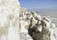 Muž v Rumunsku si na vyhlídce (vlevo) fotografuje kameny pokryté ledem, který vznikl zamrznutím vody z Černého moře na skalách u pobřeží. (Foto: ČTK/AP)
