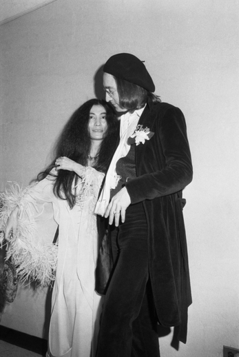 John Lennon a Yoko Ono v roce 1975. Pár se snažil v bláznivých kreacích odvést pozornost od rostoucího bříška Yoko Ono, zrovna čekala syna Seana. Yoko si vzala boa a Lennon sametový oblek, na který si nechal vyšít jméno Elvis.