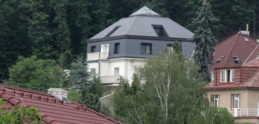 Bílá Krejčířova vila mezi stromy.