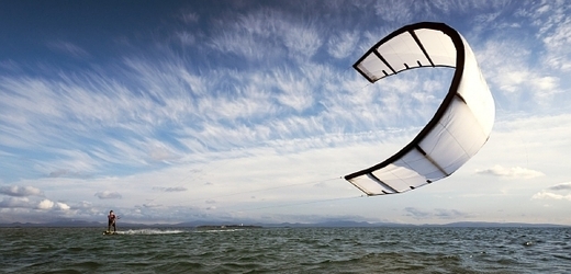 Kitesurfing je jízda po vodní hladině na speciálním prkně a v závěsu za speciálním drakem (ilustrační foto).