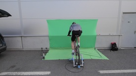 Cyklista šlapal na kole před speciálním zeleným pozadím.