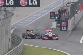 Kimi Räikkonen (vlevo) v těsném souboji s Lewisem Hamiltonem na konci boxové uličky.